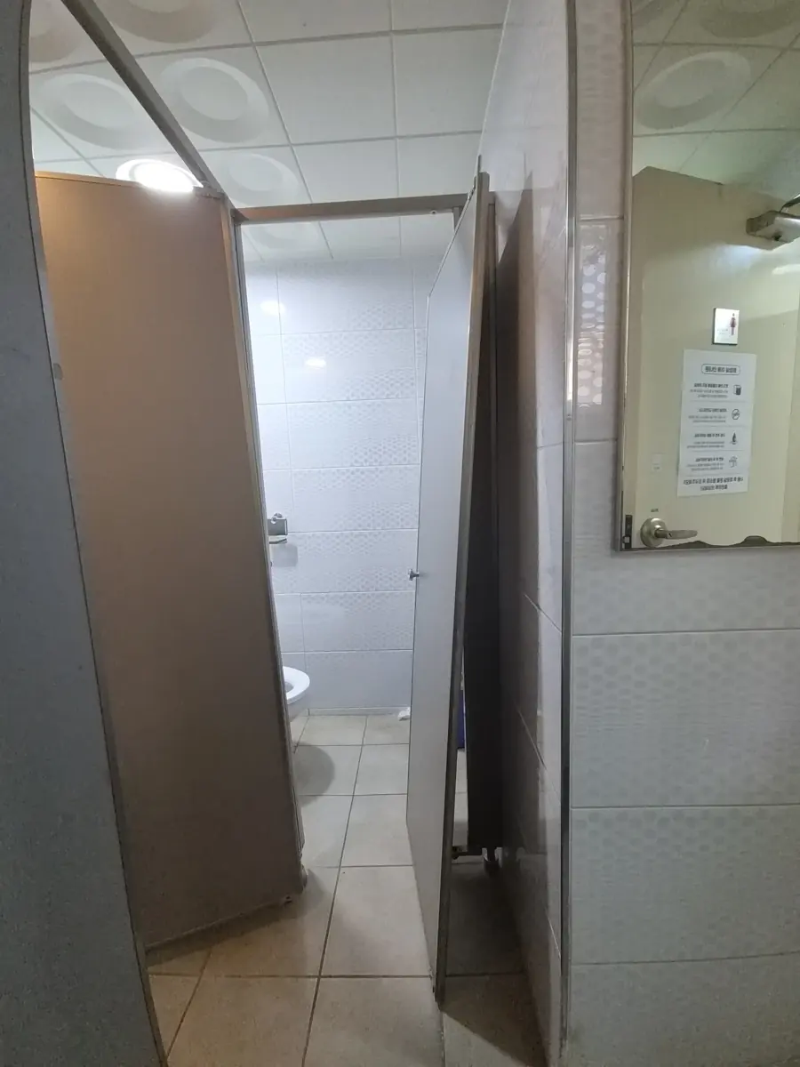 화장실칸막이떨어진문수리 열린 회색 문이 위쪽 고정이 풀려 기울어진 화장실 칸막이