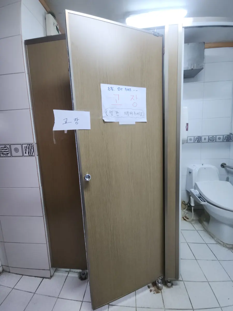 문이 열린 채 기울어져 있는 화장실칸막이수리 전 모습