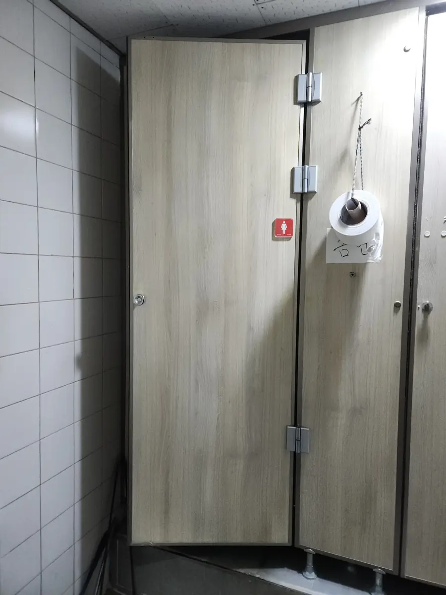 문이 열려 상부 힌지가 드러난 화장실칸막이문짝교체 대상 문